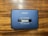 A vintage AIWA stereo cassette player with a blue casing featuring an 'AUTO REVERSE' function. The player rests on a wooden surface, showing signs of wear such as scratches.