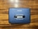 A vintage AIWA stereo cassette player with a blue casing featuring an 'AUTO REVERSE' function. The player rests on a wooden surface, showing signs of wear such as scratches.