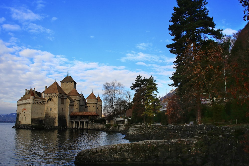 a castle sitting on top of a lake next to a forest