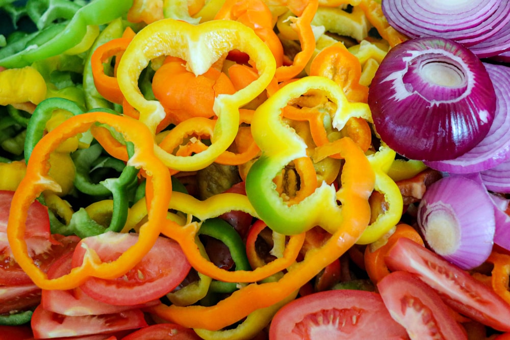 a pile of different colored peppers and onions