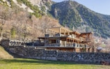 a stone wall and a house with a mountain in the background