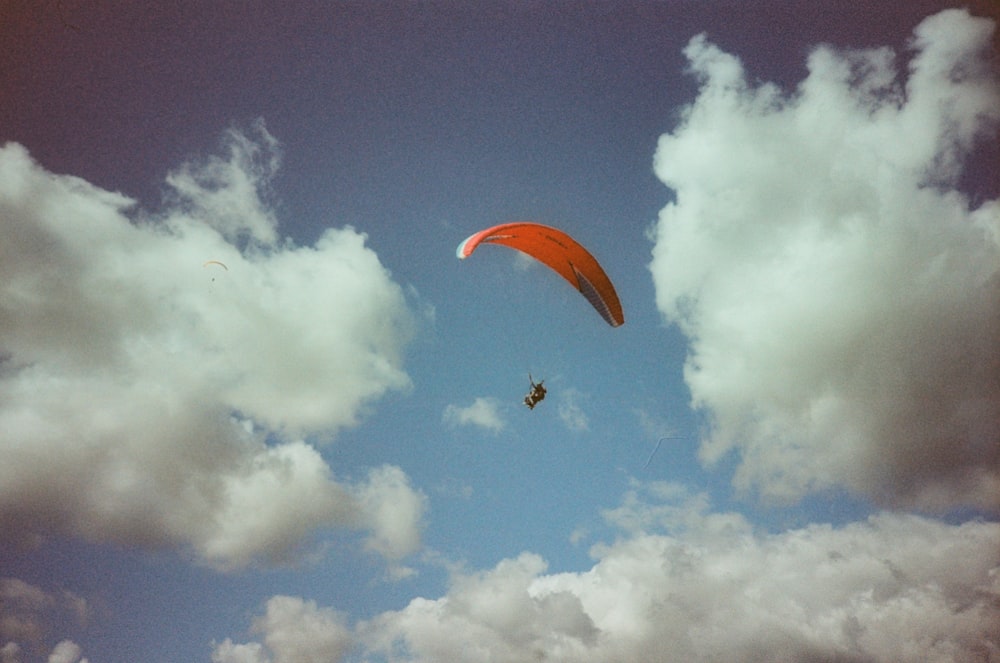 a paraglider is flying through a cloudy blue sky