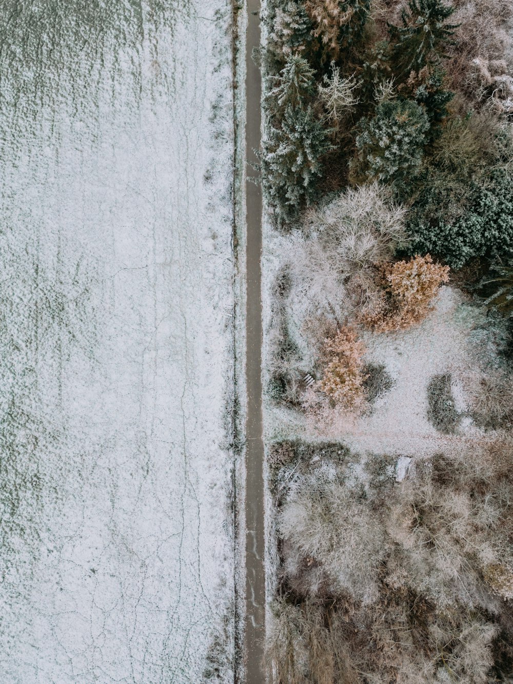 an aerial view of a snow covered road and trees