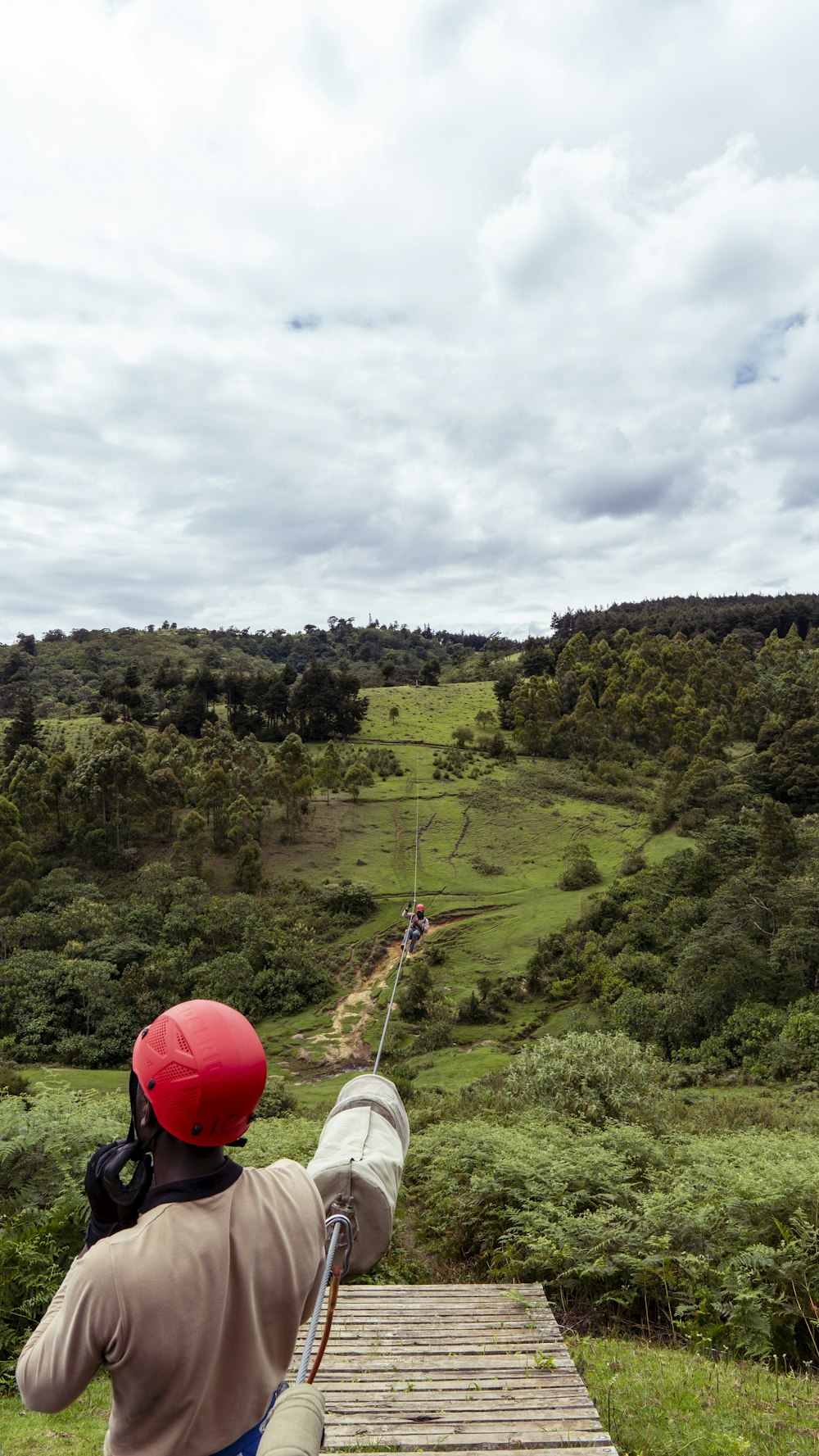 a man flying a kite over a lush green hillside