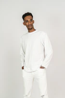 A model wearing a simple white button-up shirt paired with dark trousers in a bright studio.