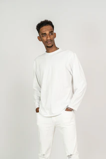 Model wearing a crisp white shirt and tailored trousers against a soft grey backdrop