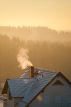 A cozy mountain cabin with smoke curling from the chimney at sunset.