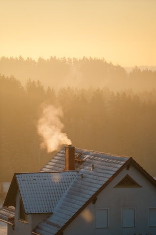 A cozy home with smoke gently rising from the chimney, indicating warmth and comfort.