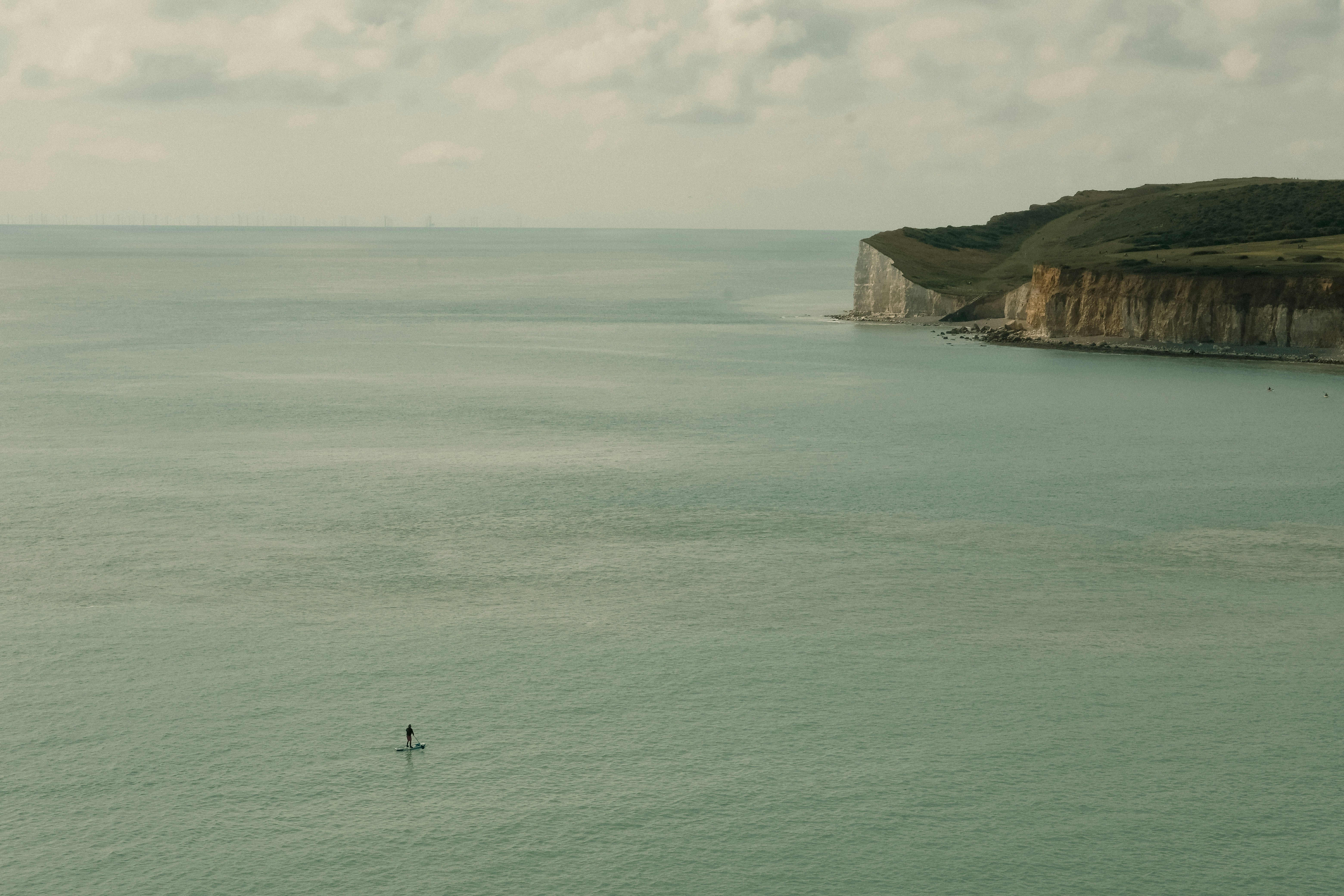Eine einsame Person, die auf einem Surfbrett mitten im Ozean steht