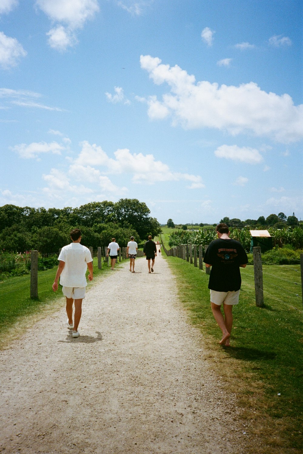 a group of people walking down a dirt road