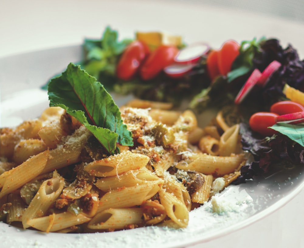 a white plate topped with pasta and vegetables