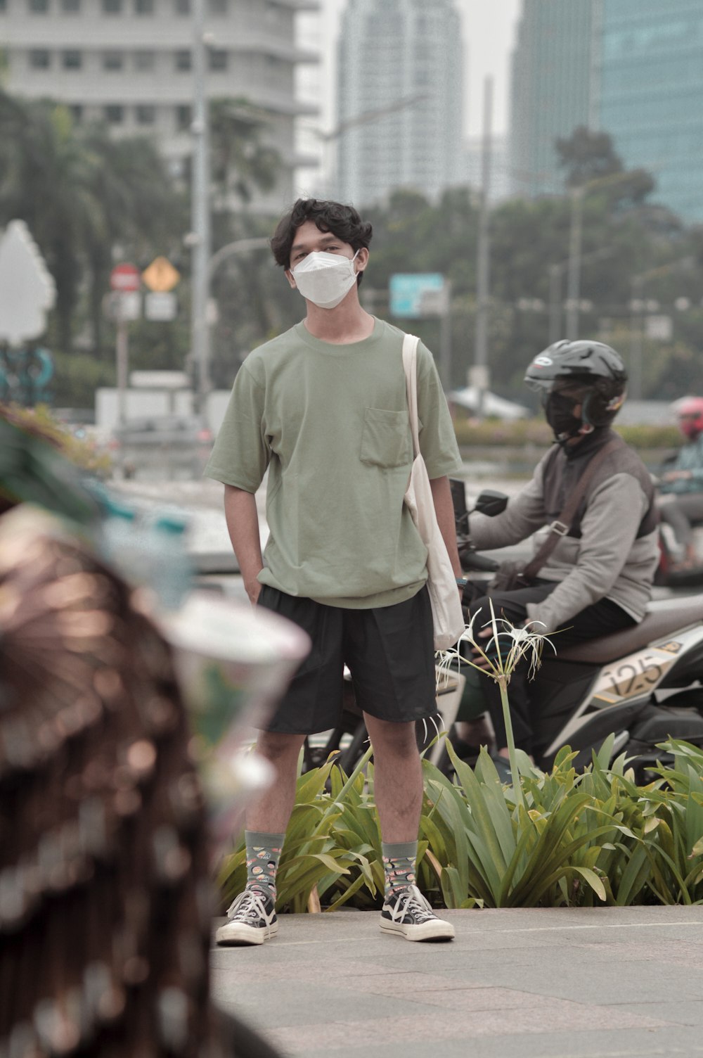 a man wearing a face mask while standing next to a motorcycle