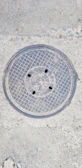 Close-up of a sturdy manhole cover with textured surface on a city street.