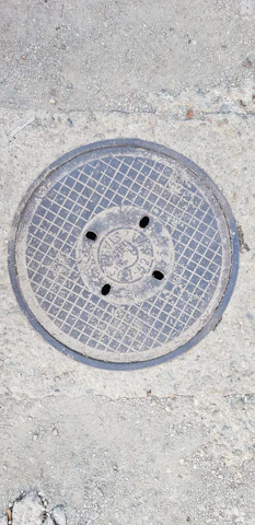 Installation of a sturdy grey FRP manhole cover on a city street, showing its lightweight design.