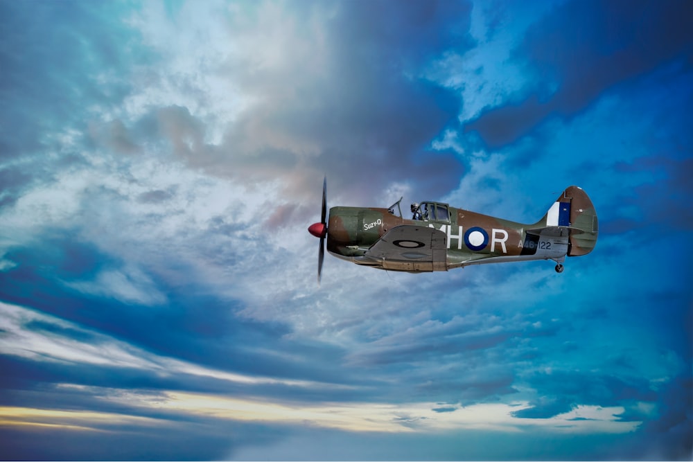 a small airplane flying through a cloudy blue sky