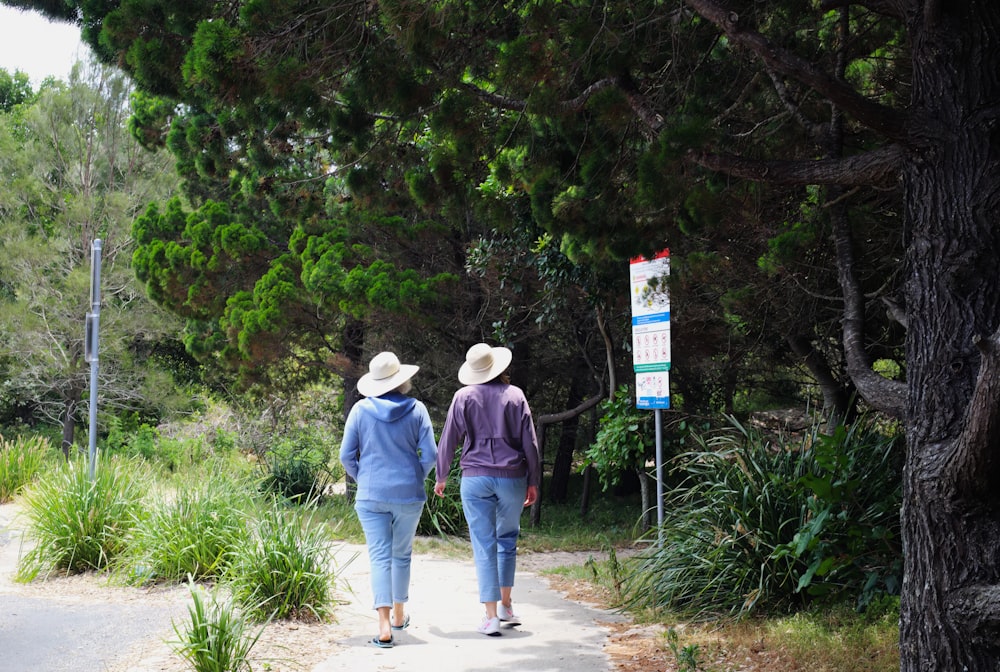 two people walking down a path in the woods