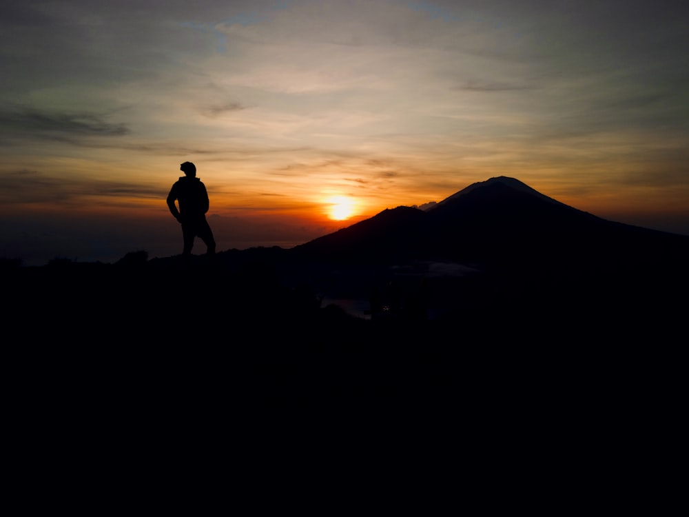 a man standing on top of a mountain at sunset