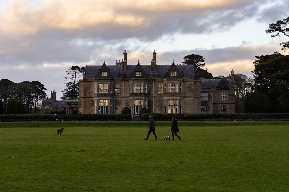 two people and a dog walking in front of a large building