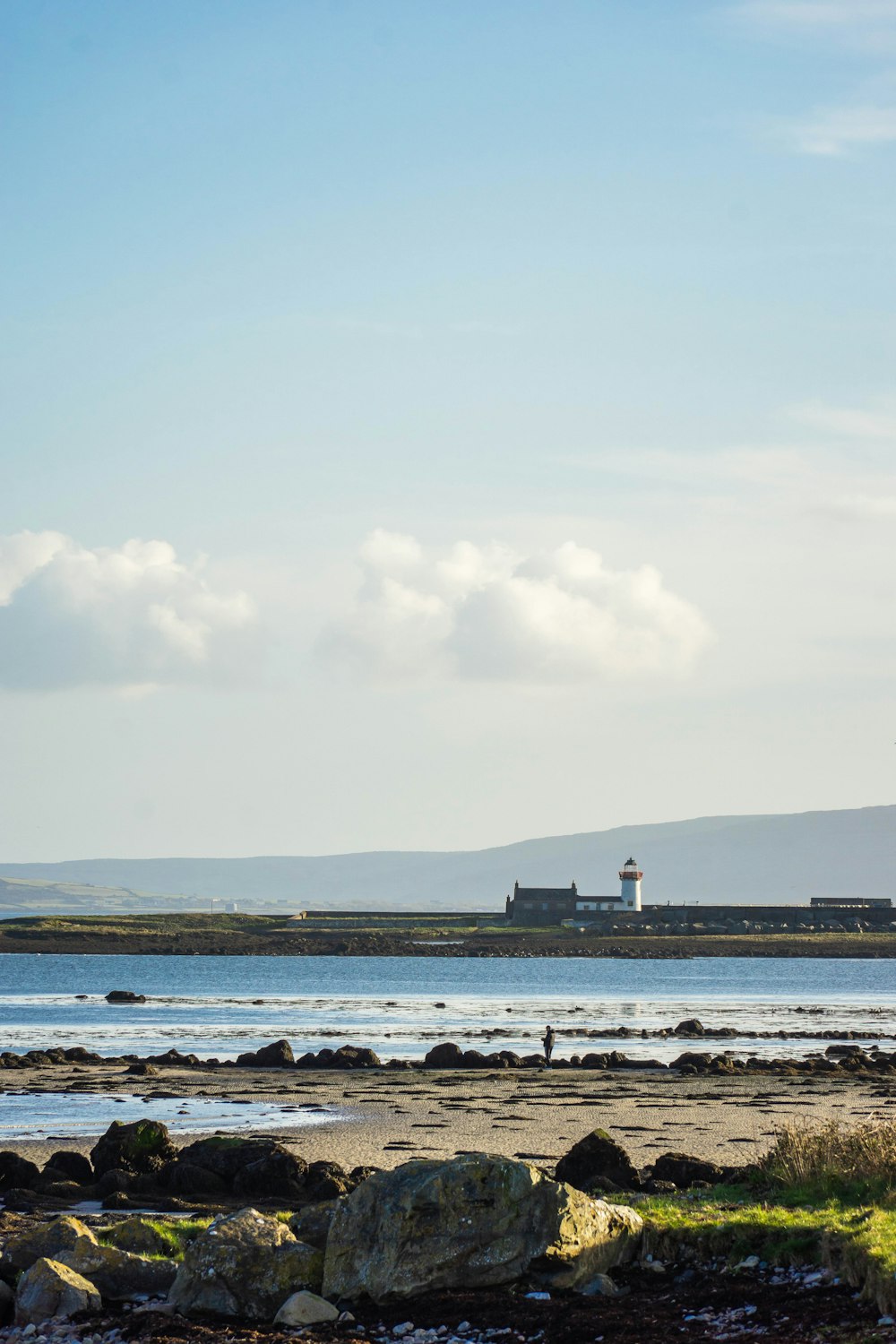 a lighthouse on a rocky shore with a body of water in the background