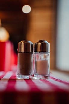 Close-up of a custom 3D-printed salt and pepper set in warm terracotta tones on a wooden table.