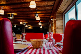 A cozy, rustic restaurant interior bathed in deep crimson and forest green tones.