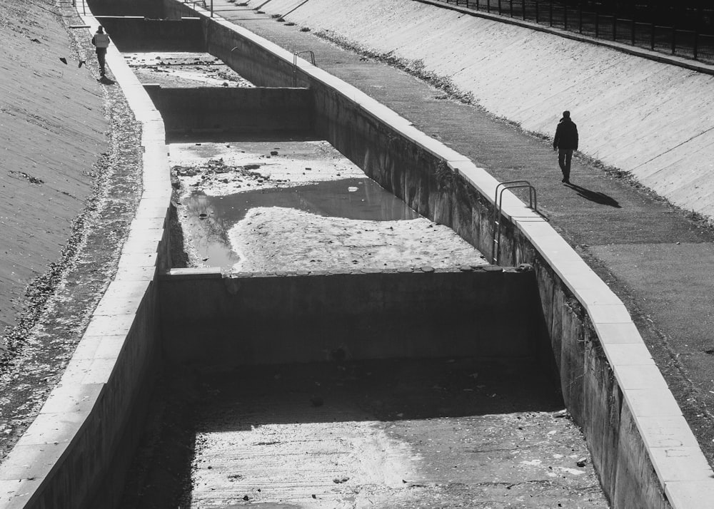 a man walking down a road next to a large trench