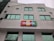 The image depicts a modern building with large green-tinted windows. A colorful sign with the word 'mBank' is prominently mounted near the center of the facade. The building's architecture features geometric shapes and a light gray exterior.