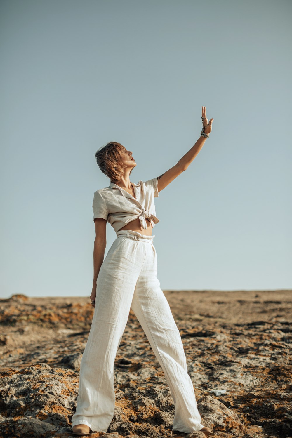 a woman standing on top of a dirt field