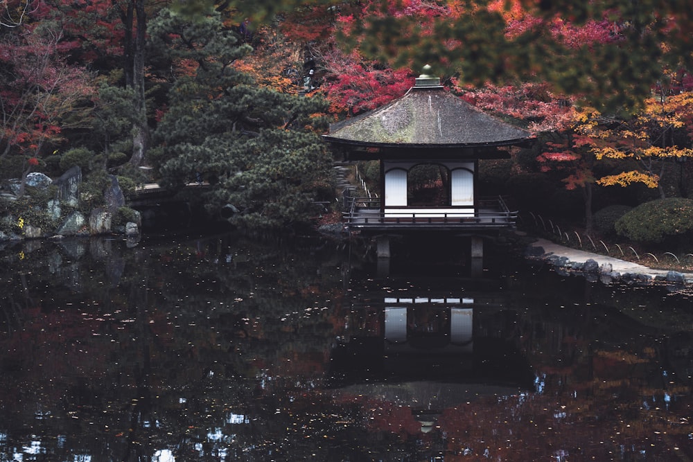 a gazebo in the middle of a pond surrounded by trees