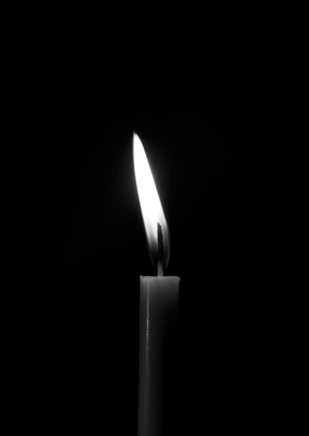 a lit candle with a black background
