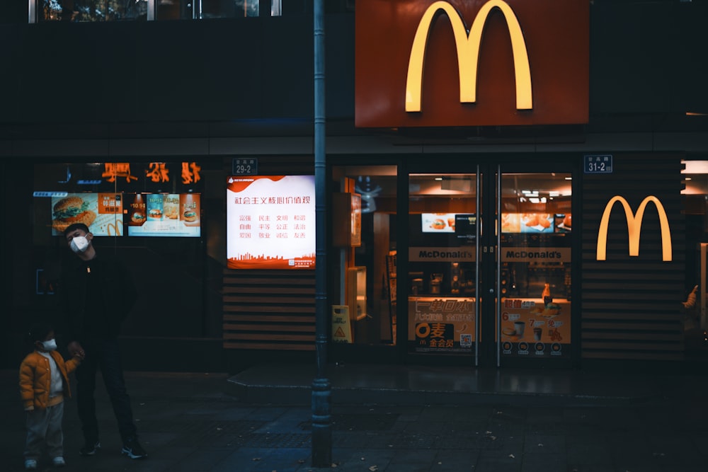 a man standing on a sidewalk in front of a mcdonald's