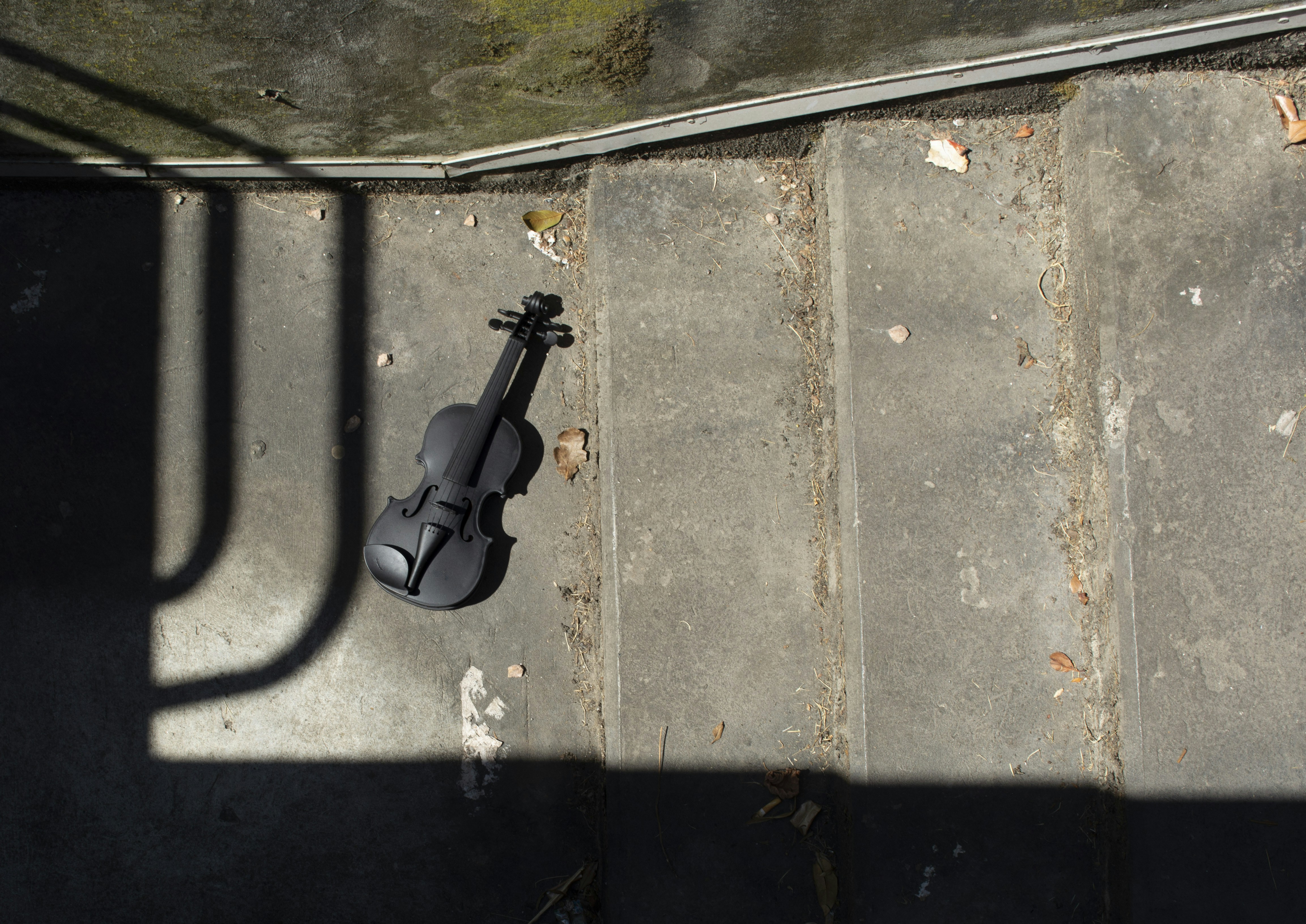 Un violín tendido en el suelo junto a una pared