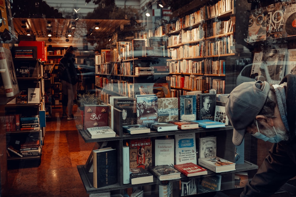 a man looking through a window at a book store