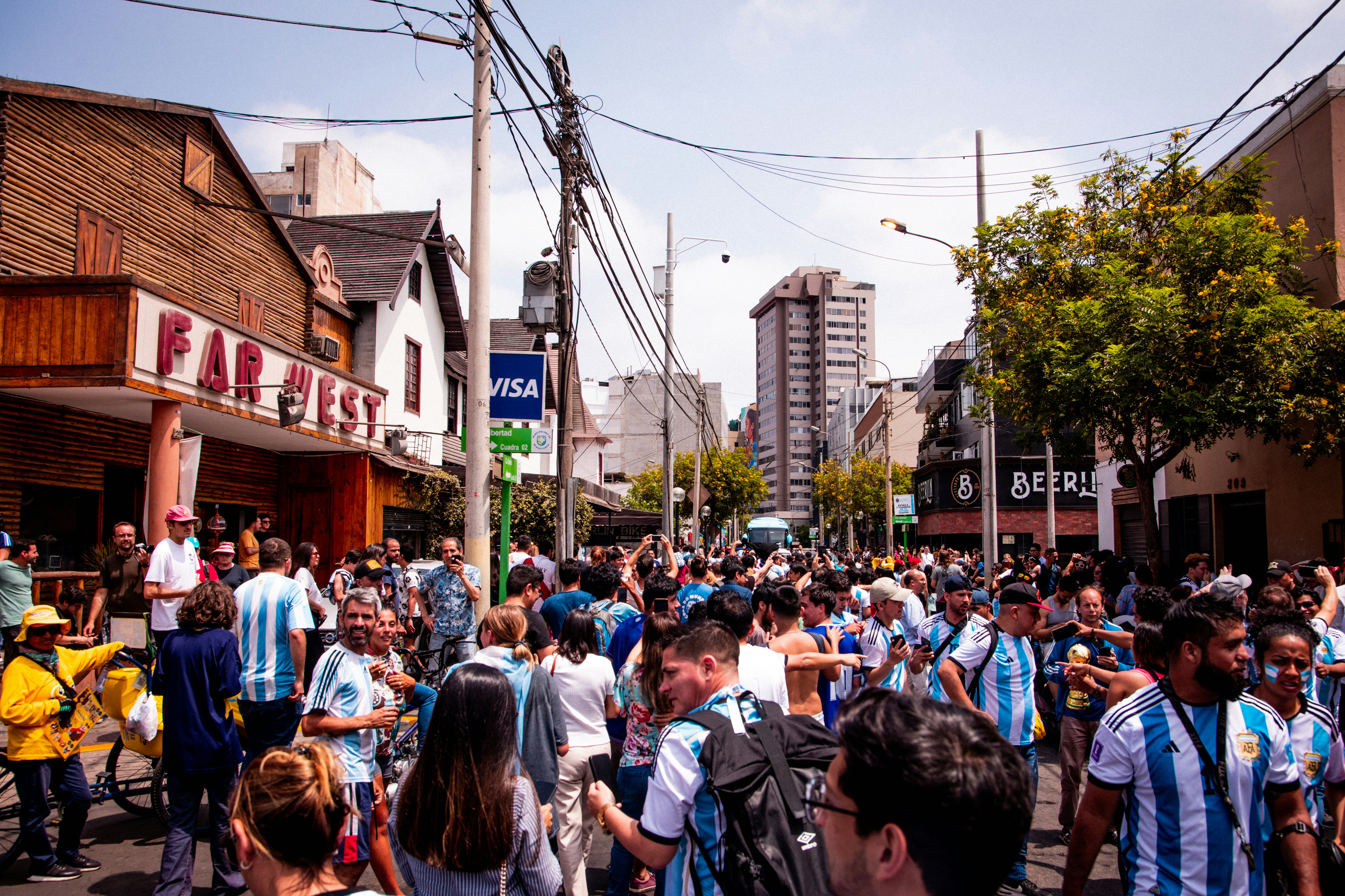 a crowd of people walking down a street next to tall buildings