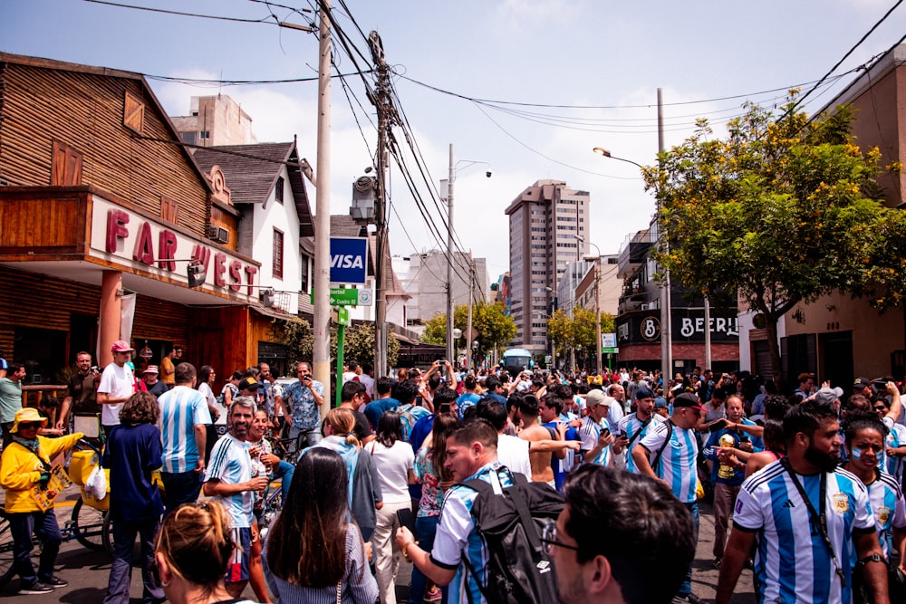 a crowd of people walking down a street next to tall buildings