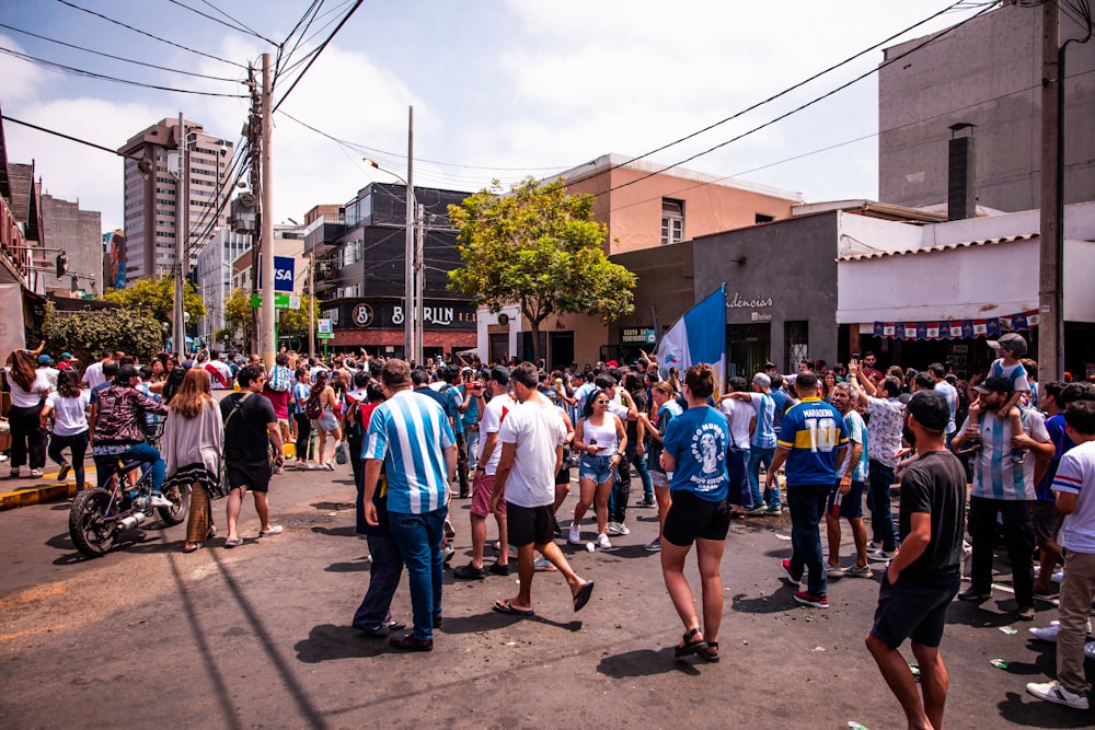 a group of people walking down a street next to tall buildings