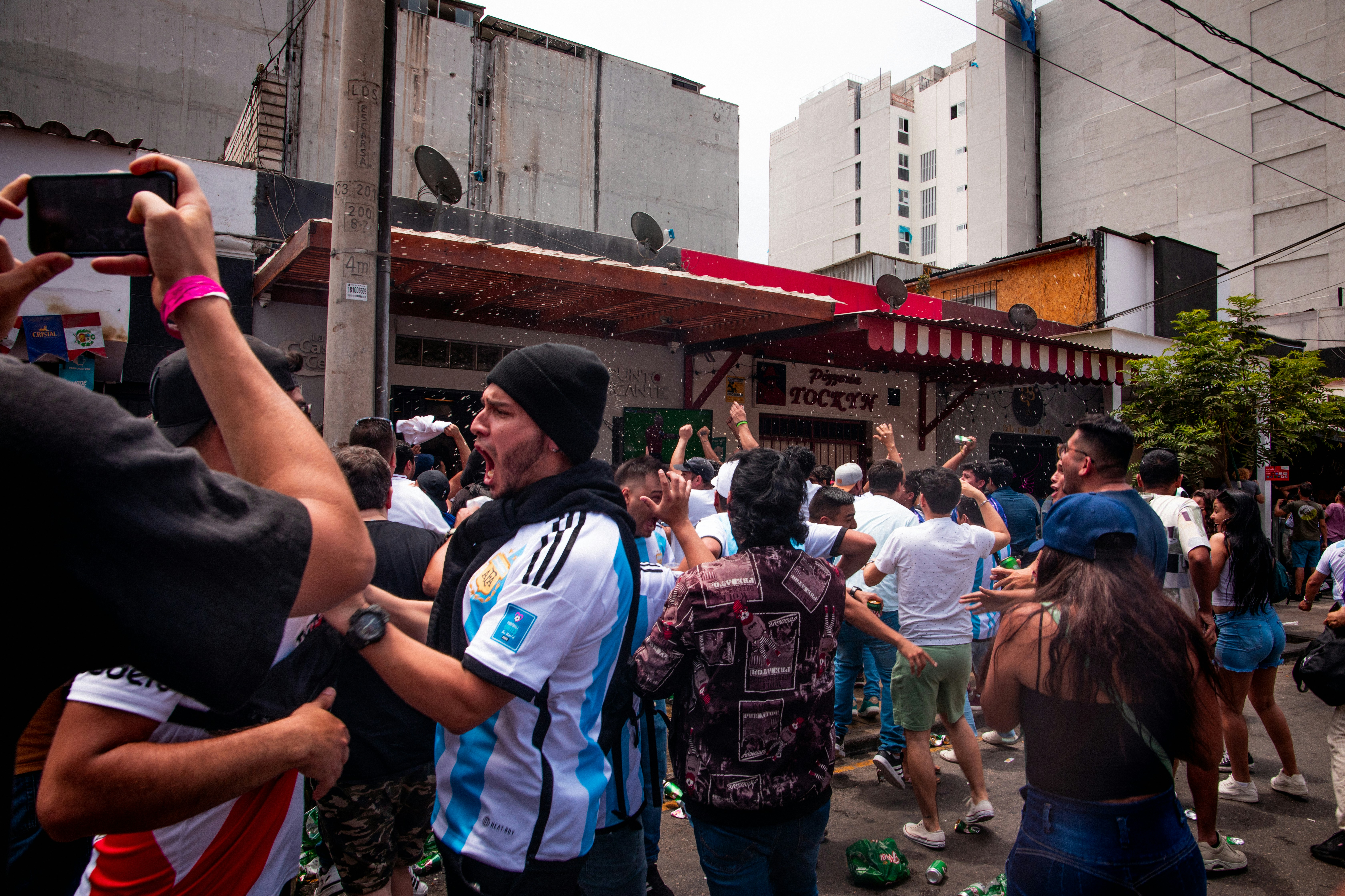 a crowd of people walking down a street next to tall buildings