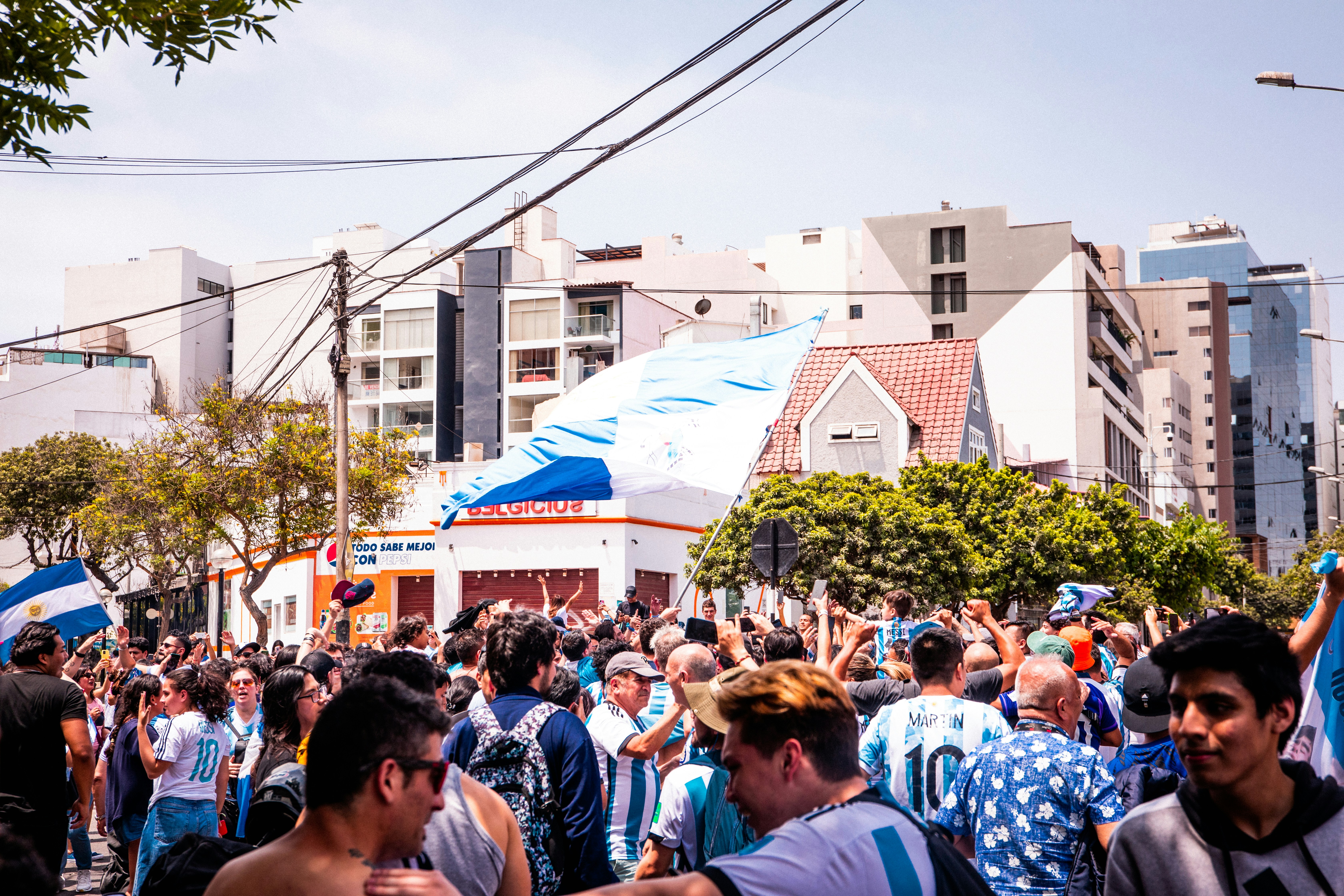 a crowd of people walking down a street next to tall buildings