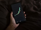 a person holding a cell phone with a chart on the screen