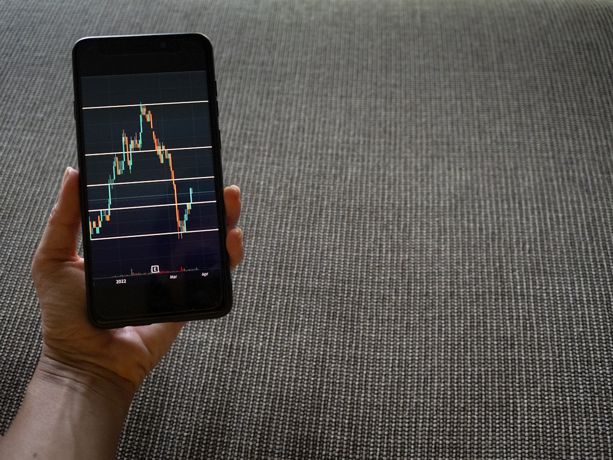 Person holding smartphone showing stock trading chart representing mobile banking growth