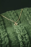 Close-up of a delicate gold necklace resting on a soft beige fabric.