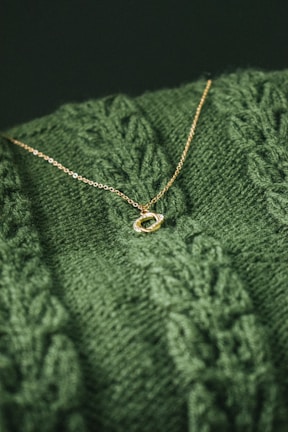 A close-up of a handcrafted gold necklace on a soft fabric.