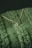 A close-up of an elegant pendant necklace displayed on a soft fabric background.