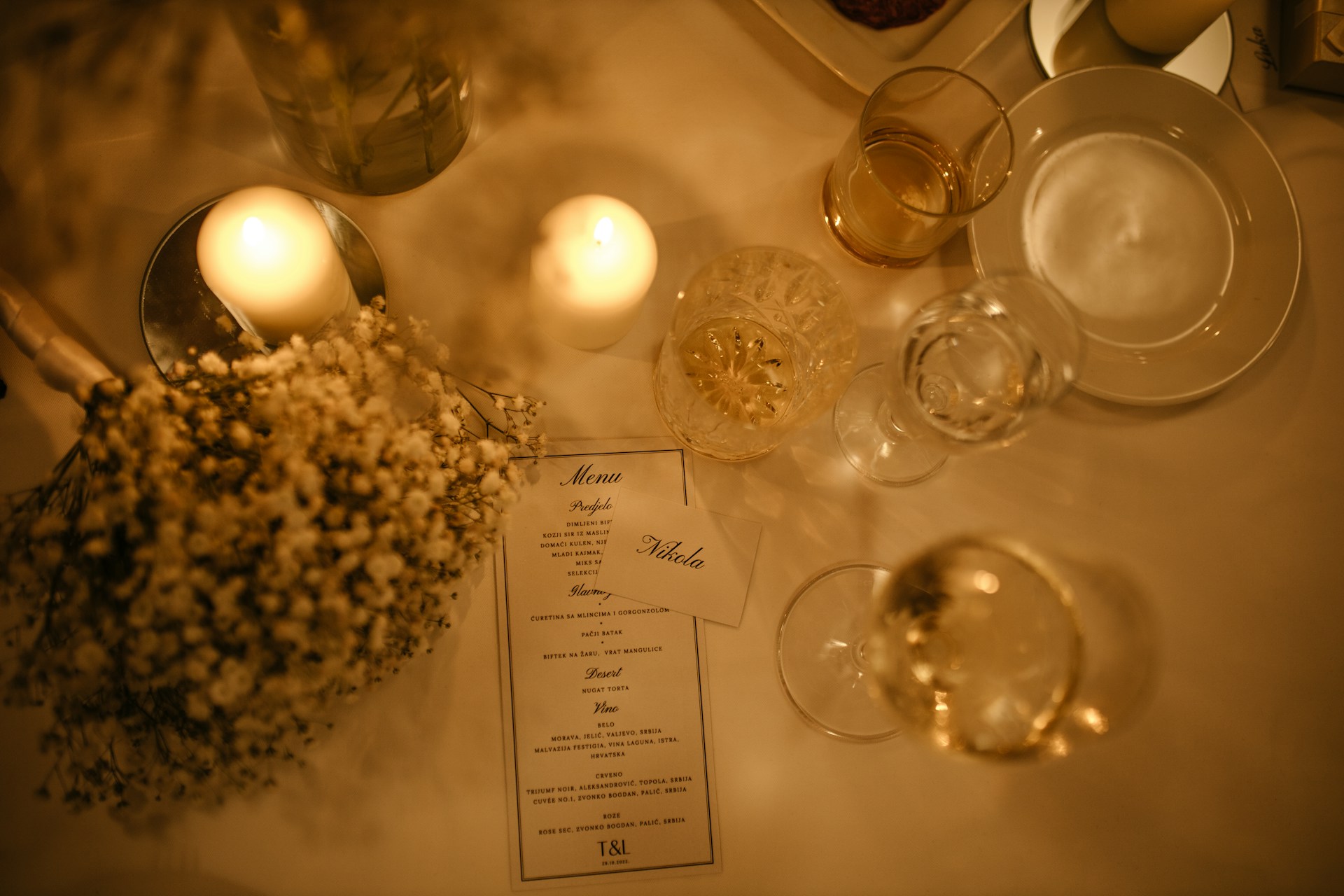 a table with a menu, wine glasses, and flowers