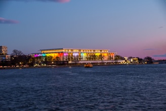 a large building is lit up at night by the water