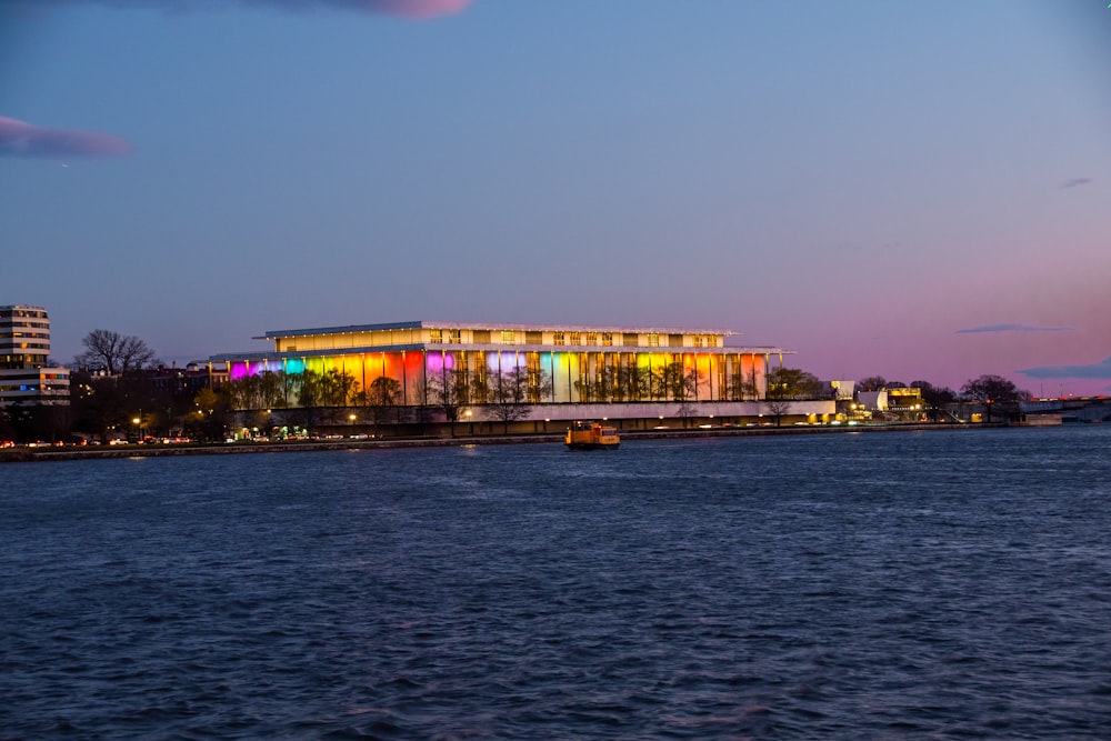 a large building is lit up at night by the water