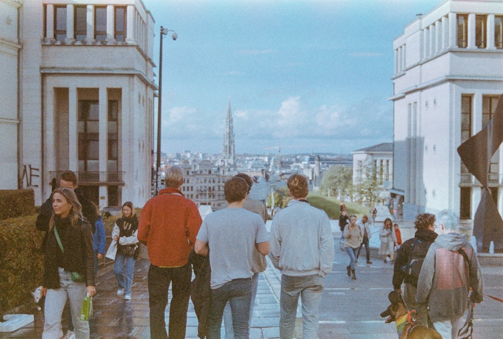 a group of people walking down a street next to tall buildings