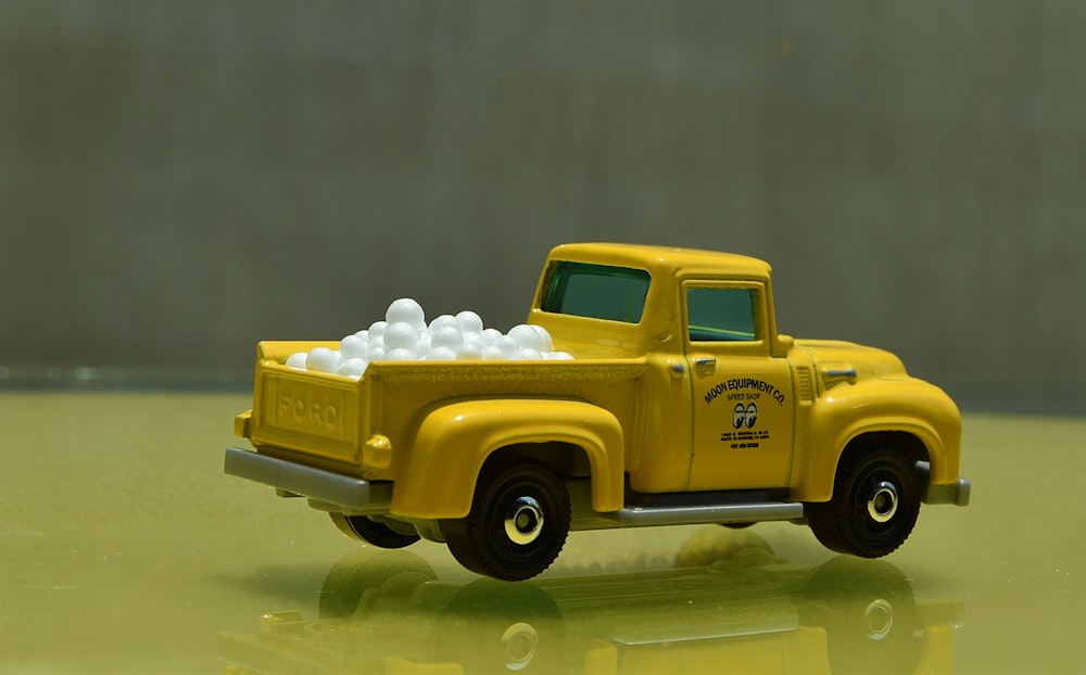a yellow toy truck filled with white balls