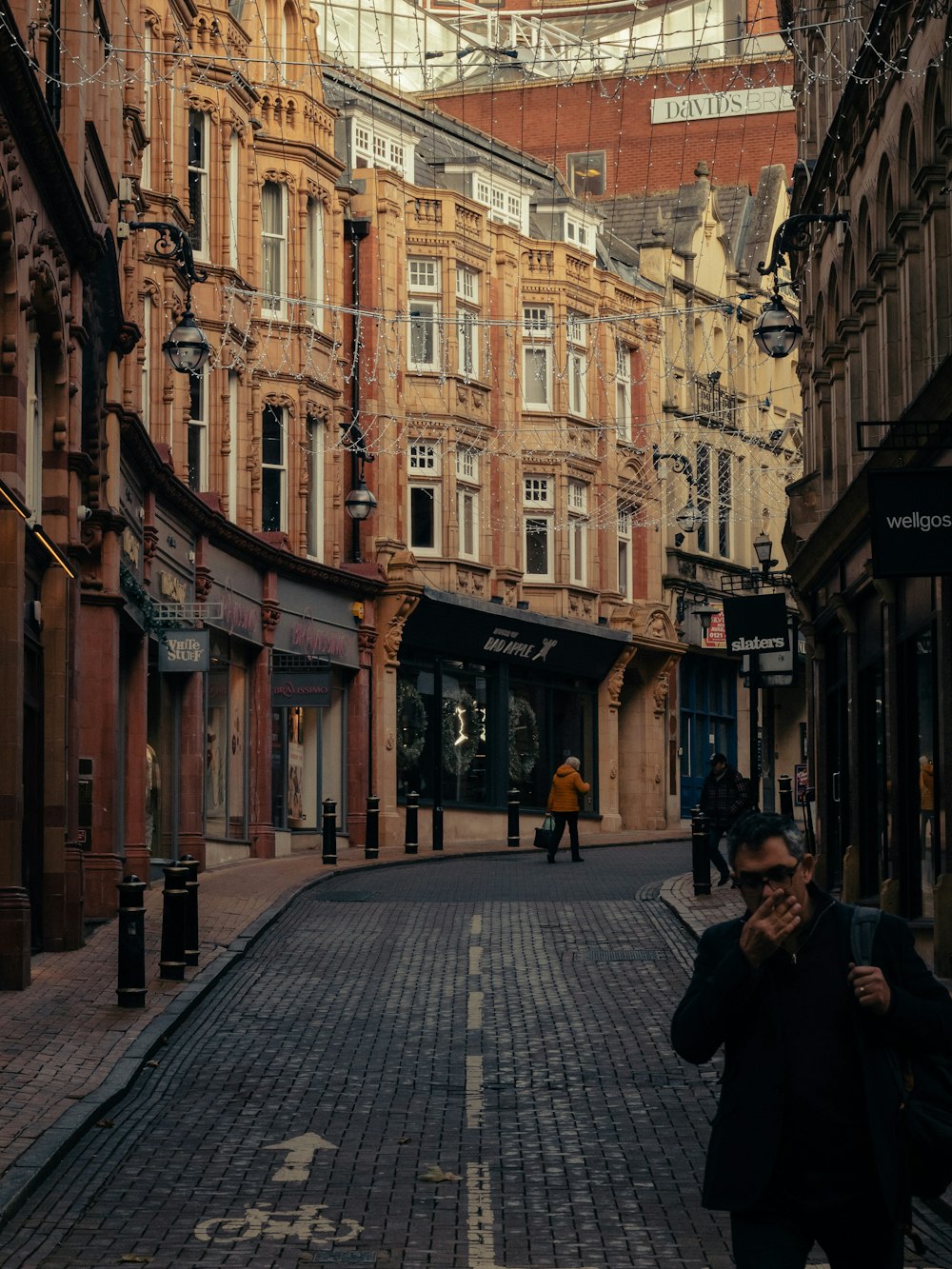 a man walking down a street next to tall buildings