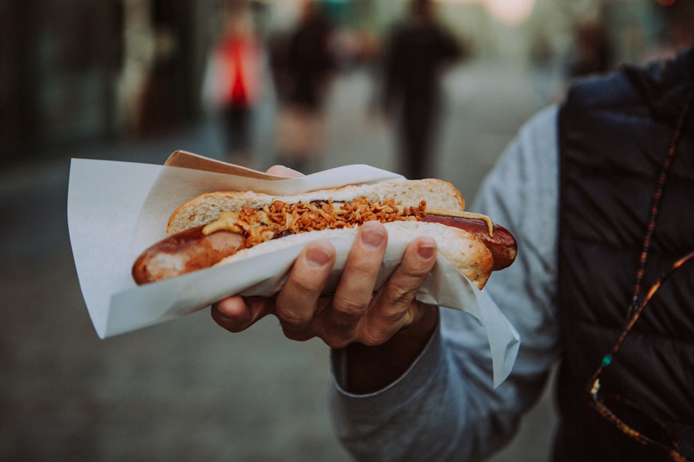 a person holding a hot dog in their hand